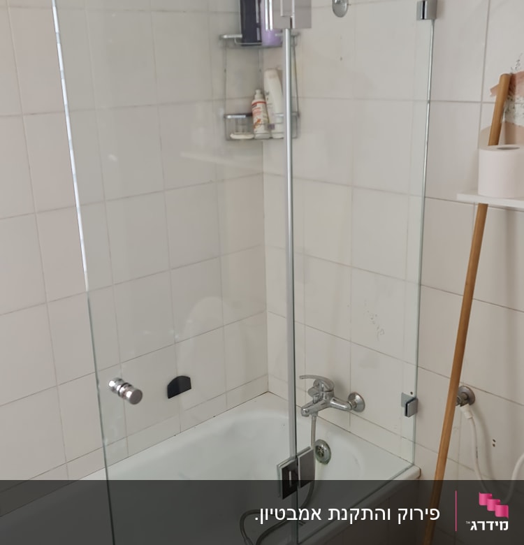 מקלחת עם אמבטיה, דלת זכוכית ומדף עם מוצרי טיפוח